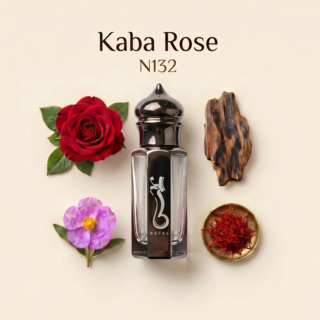 A perfume bottle labeled 'Kaba Rose N132' centered on a warm beige background, surrounded by a red rose, a purple flower, a piece of driftwood, and a small dish of red saffron. The bottle is clear glass with a glossy black cap and a black central label featuring a white snake-like emblem.