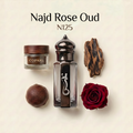 A perfume fragrance presentation labeled 'Najd Rose Oud N125' on a light beige background, featuring a small jar with a dark wood lid labeled COPAHU, a dark glass perfume bottle with a silver snake emblem, a brown spherical object, a piece of dark wood, and a deep red rose.